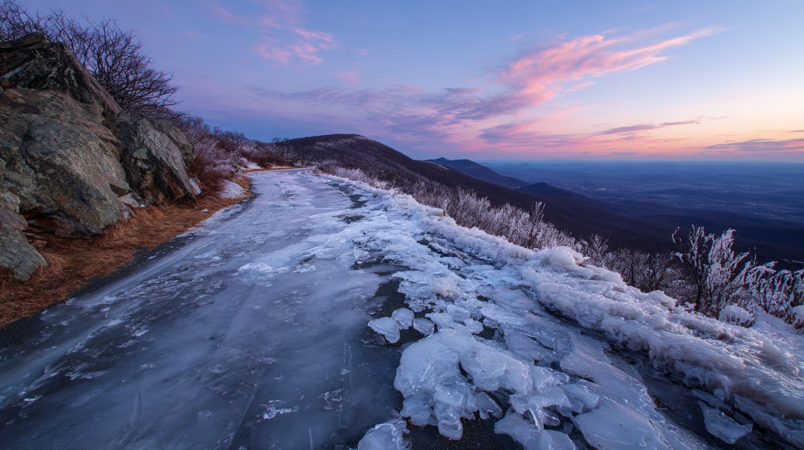 Frozen roadway on Skyline Drive with mountains and sunrise in the background