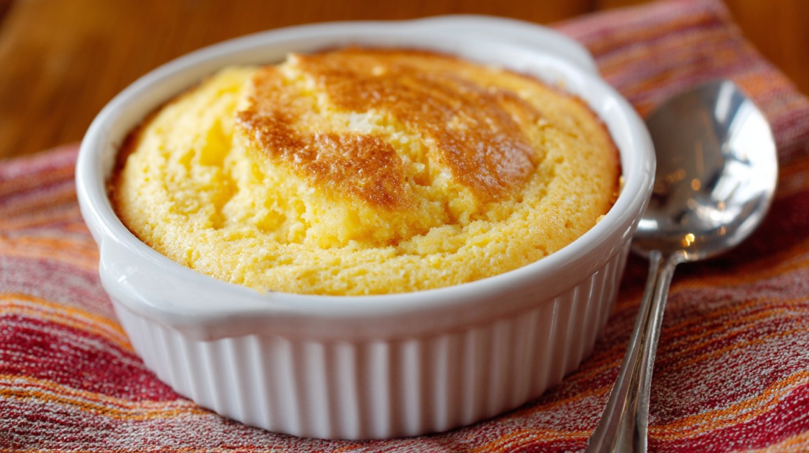 Freshly baked spoonbread in a white ramekin with a golden top