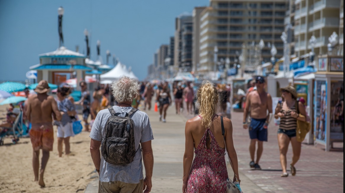 Crowds walking along the Virginia Beach boardwalk on a sunny summer day.