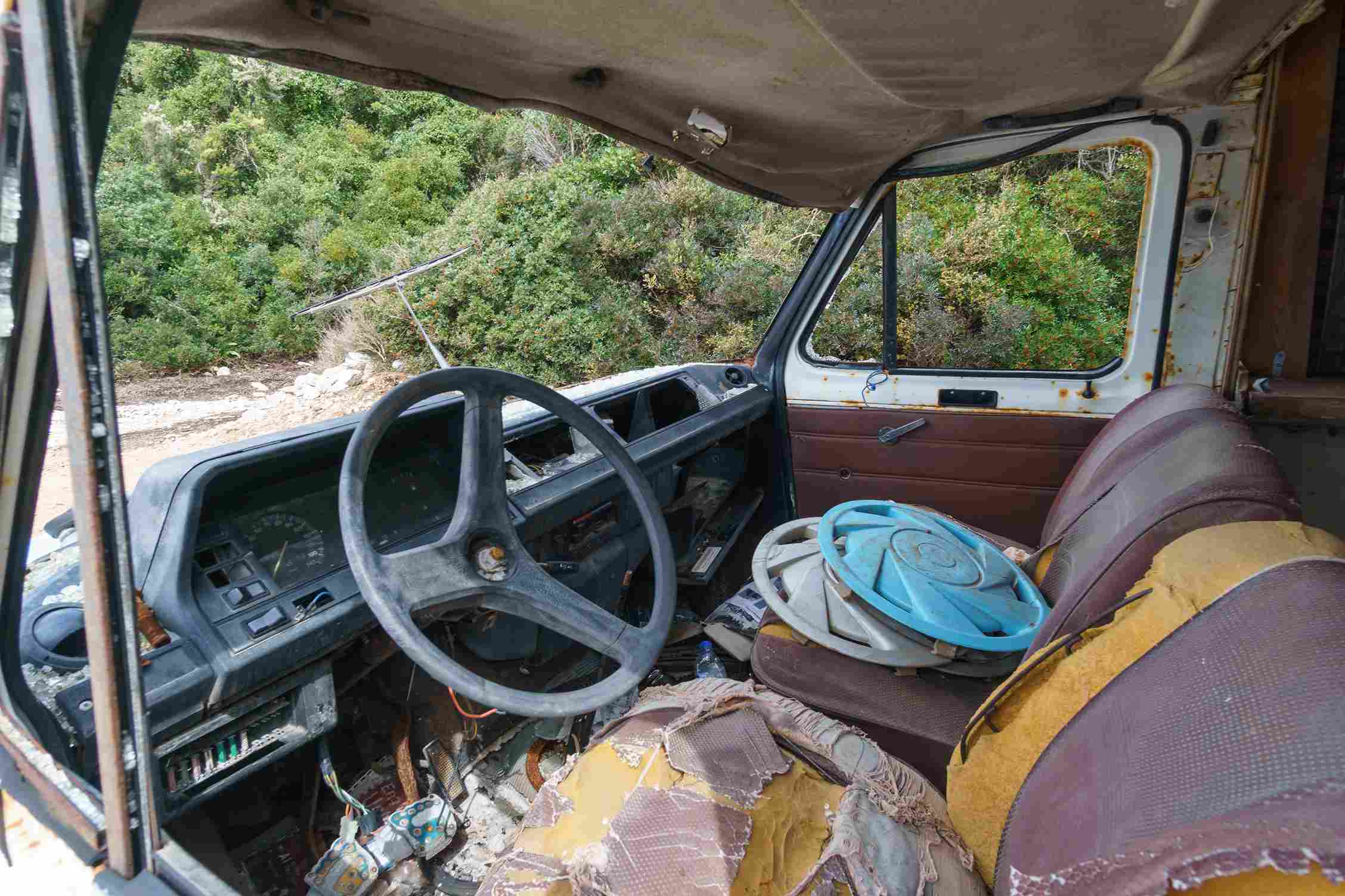 Damaged vehicle interior with worn seats and aging dashboard components